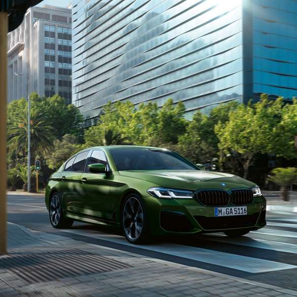 BMW M550i xDrive G30 LCI Facelift 2020, вид вид спереди в три четверти, в движении BMW M550i xDrive G30 LCI Facelift 2020, BMW Individual "Зеленый Эрмес металлик", на городской улице, вид спереди в три четверти