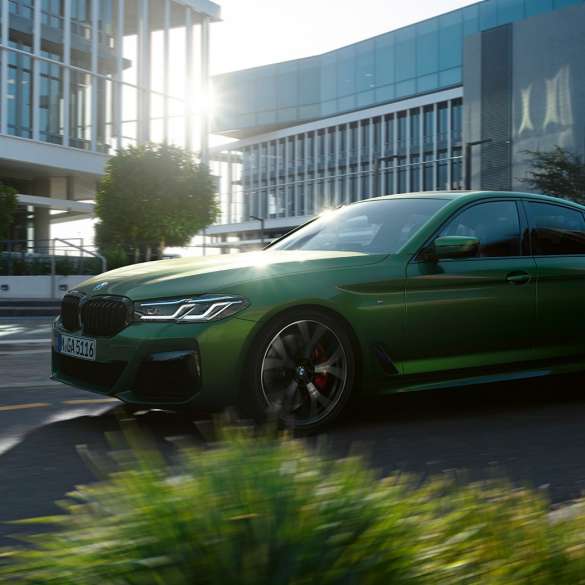 BMW M550i xDrive G30 LCI Facelift 2020, вид сбоку в движении BMW M550i xDrive G30 LCI Facelift 2020, BMW Individual "Зеленый Эрмес металлик", на городской улице, вид сбоку