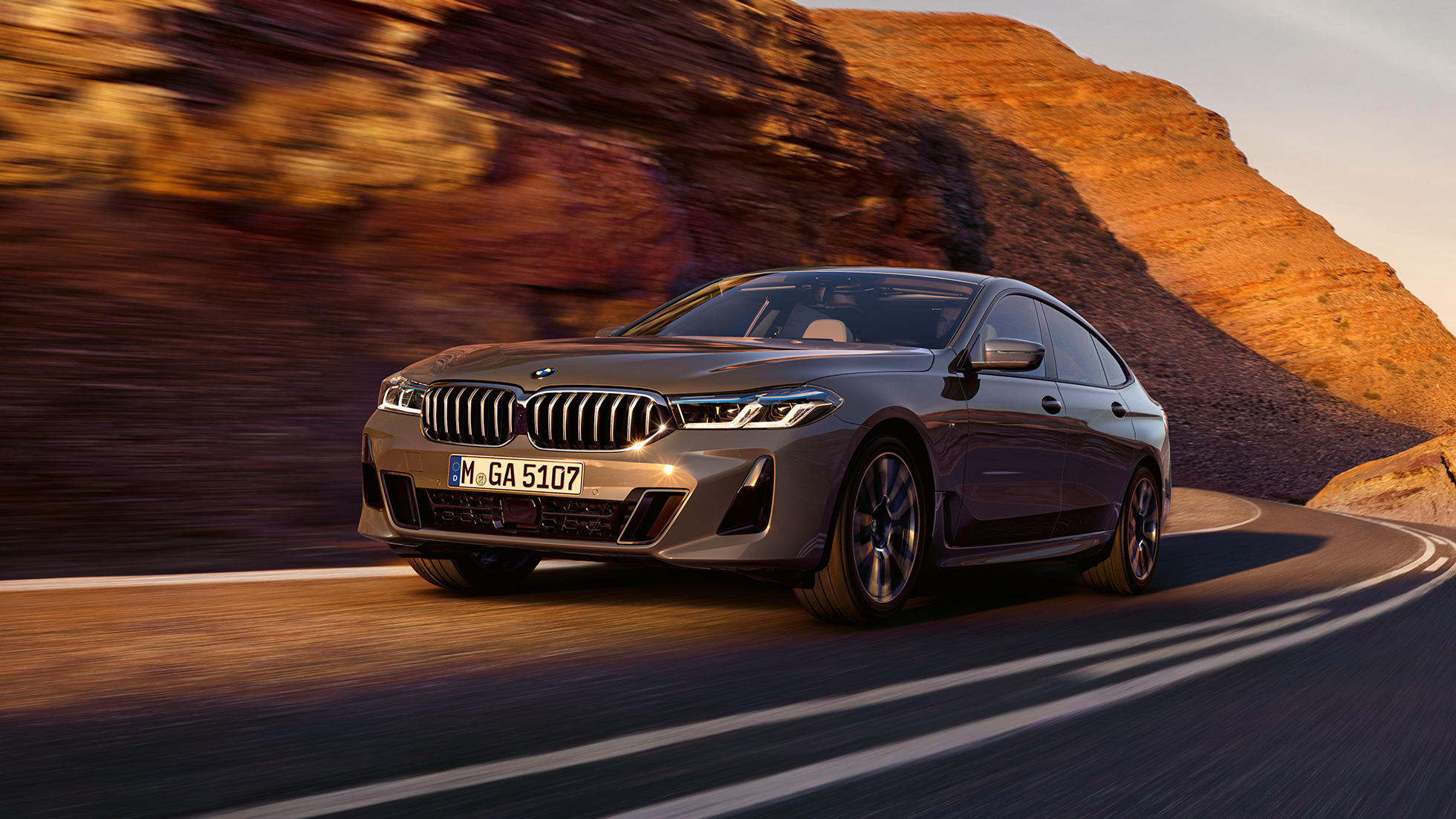 BMW 6 серии GT G32 2020 года BMW 6 серии GT 640i xDrive G32 2020 года, цвет «Серый Бернина», в движении на фоне природы, вид спереди с поворотом в три четверти