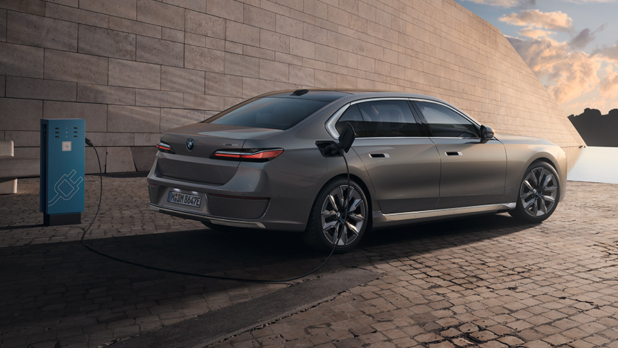 BMW i7 G70, вид в три четверти сбоку сзади BMW i7 G70, "Серый Оксид металлик", вид в три четверти сбоку сзади на зарядной станции