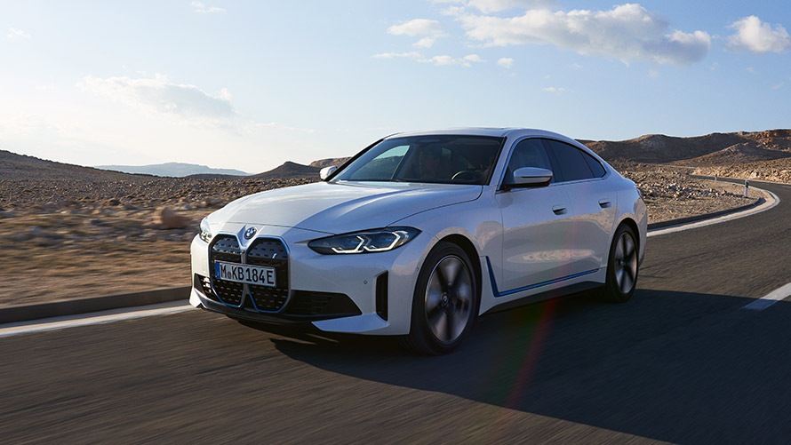 BMW i4 G26 первого поколения, вид спереди с поворотом в три четверти BMW i Серии BMW i4 G26 первого поколения, вид спереди в три четверти, в движении