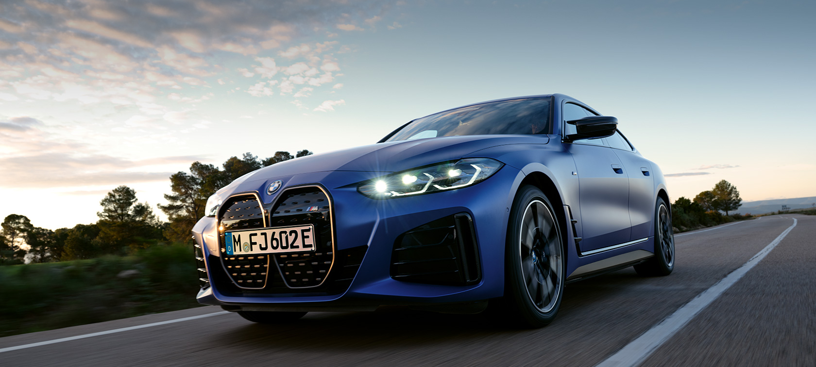 BMW i4 M50 G26 2021, вид сбоку перед каменистым пейзажем BMW i4 M50 G26 2021 "Морозный Синий Портимау металлик" BMW Individual, вид сбоку перед каменистым пейзажем