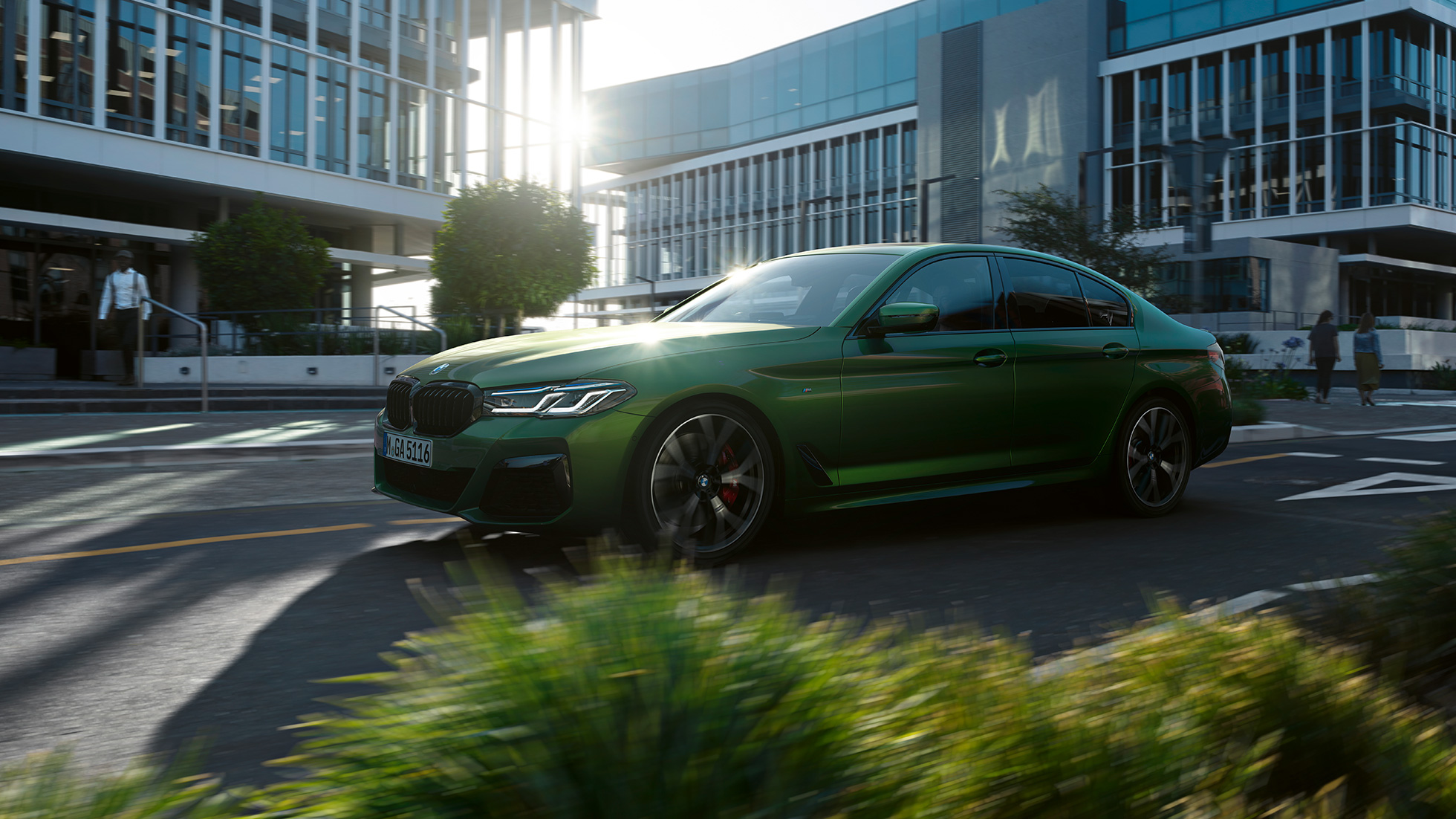 BMW M550i xDrive G30 LCI Facelift 2020, вид сбоку в движении BMW M550i xDrive G30 LCI Facelift 2020, BMW Individual "Зеленый Эрмес металлик", на городской улице, вид сбоку