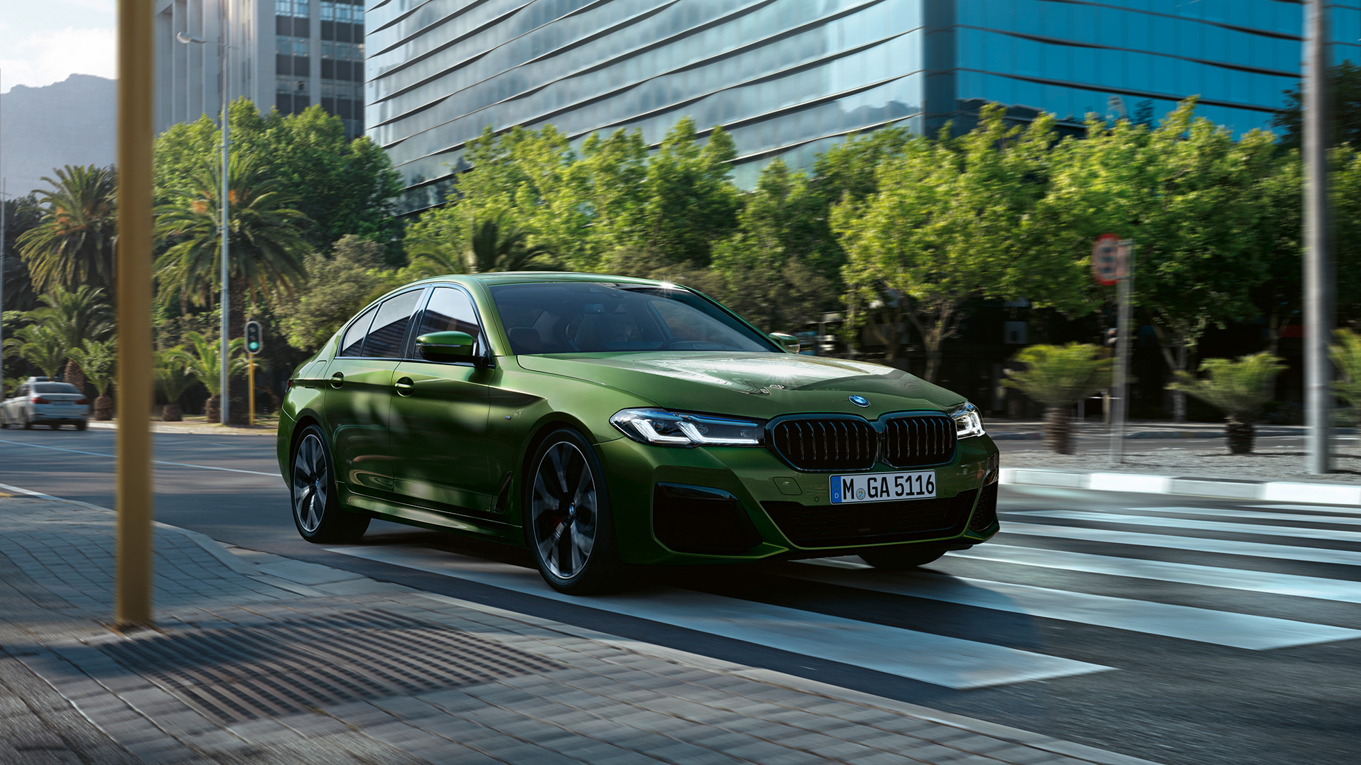 BMW M550i xDrive G30 LCI Facelift 2020, вид вид спереди в три четверти, в движении BMW M550i xDrive G30 LCI Facelift 2020, BMW Individual "Зеленый Эрмес металлик", на городской улице, вид спереди в три четверти
