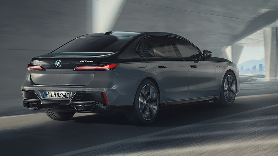 BMW M760e xDrive G70 с пакетом M Performance BMW M760e xDrive G70 с пакетом M Performance едет по улице, двухцветная окраска кузова BMW Individual (черный металлик Black Sapphire и серый металлик Dravite Grey), вид в 3/4
