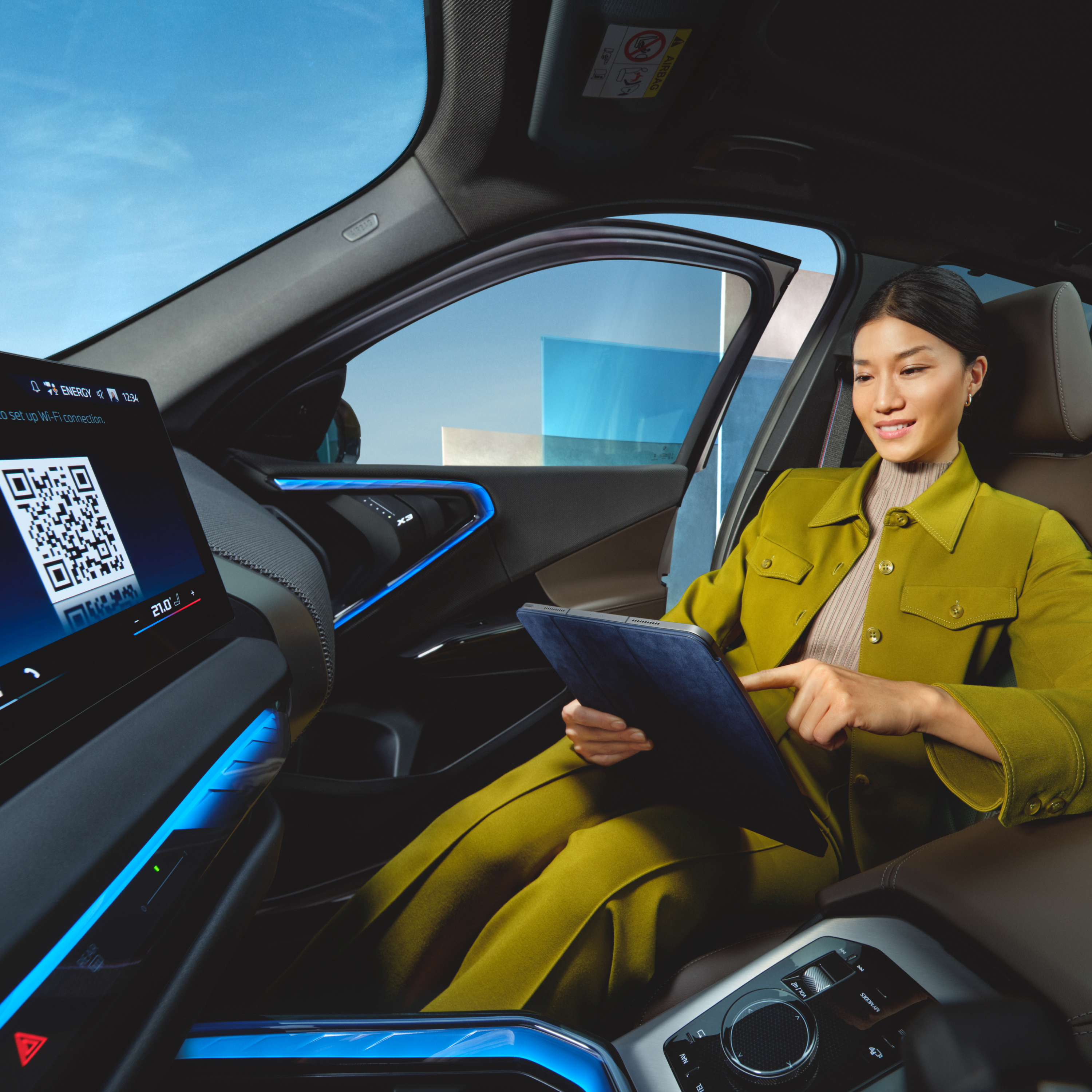 BMW көлігінде отырған адам планшетті пайдаланып жатыр